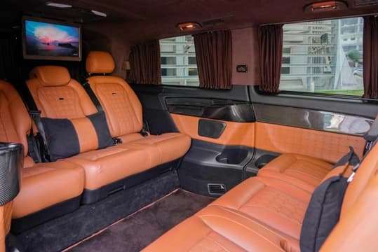 Salon arrière de la Mercedes-Benz V250 Falcon Edition en cuir fauve avec écran de divertissement, rideaux d'intimité et éclairage d'ambiance
