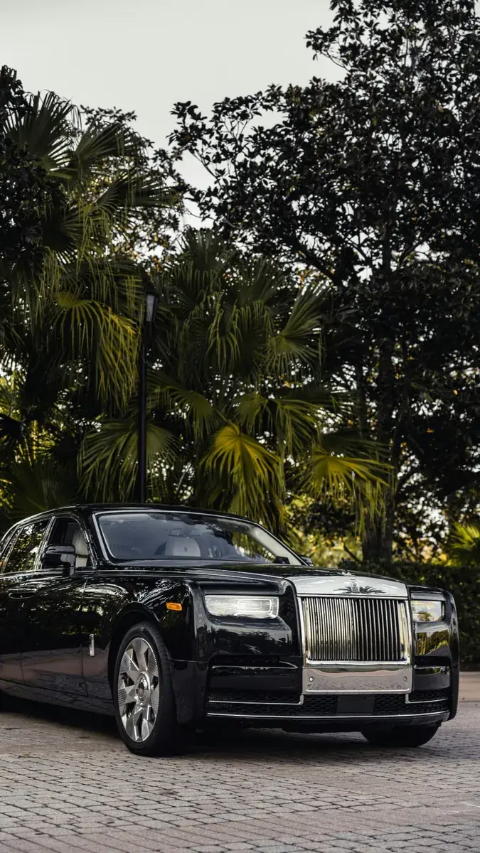 Black Rolls-Royce Phantom chauffeur car front exterior view with palm trees
